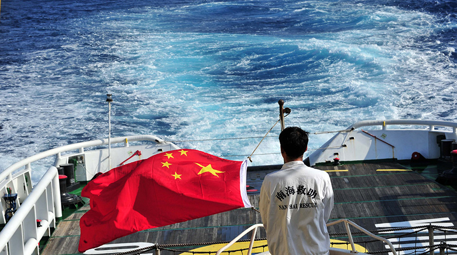 3月18日，水手李國(guó)棟在南海救101輪船甲板后部升起國(guó)旗。新華社記者 趙穎全攝